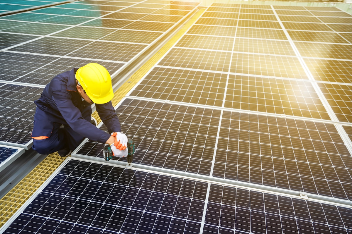 Instalator mocujący panel fotowoltaiczny na konstrukcji dachowej
